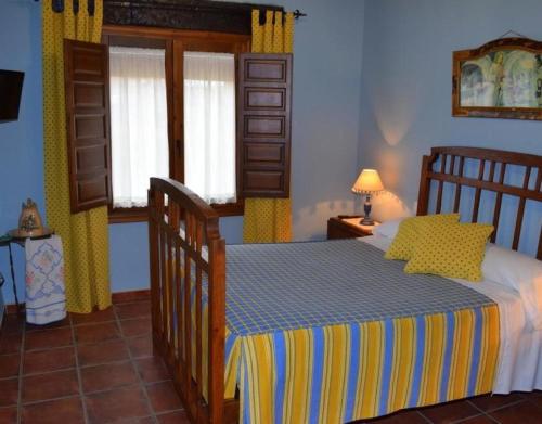 a bedroom with a bed with yellow and blue sheets at Casa Rural La Era in Aldeanueva de Barbarroya