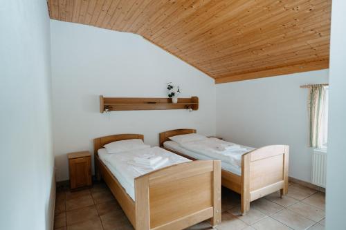 two twin beds in a room with wooden ceilings at Bouda Malenovice in Malenovice
