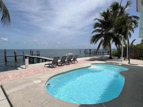 a swimming pool with two chairs and the ocean at Tropical Sunsets in Marathon