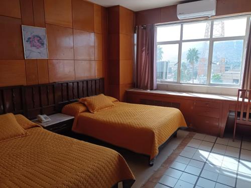 a bedroom with two beds and a window at Hotel Rio Nazas in Torreón