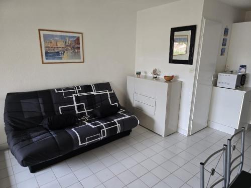 ein Wohnzimmer mit einem schwarzen Sofa und einem Kühlschrank in der Unterkunft Cap d'Agde - T2 lumineux piscine et tennis in Cap d'Agde