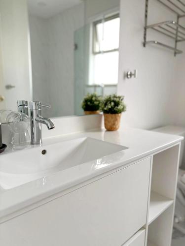 a white bathroom with a sink and a mirror at Vivi's Home in Vancouver