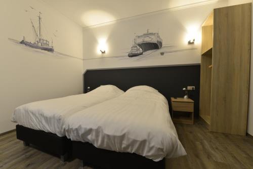 - une chambre dotée d'un lit avec des draps blancs et des bateaux sur le mur dans l'établissement Havenzicht Westkant, à Dinteloord