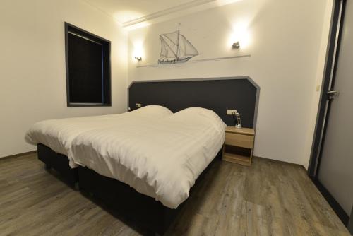 sypialnia z dużym białym łóżkiem i oknem w obiekcie Havenzicht Westkant w mieście Dinteloord