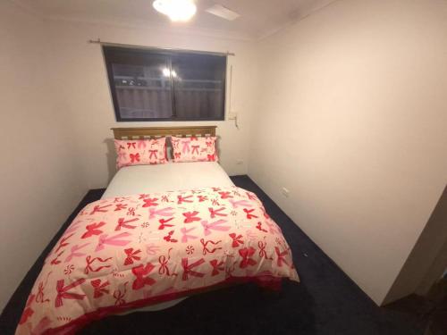 a small bedroom with a bed with a red comforter at Dalyellup 2BR accommodation-Rear Guest house Unit- Walkable to major supermarkets in North Boyanup
