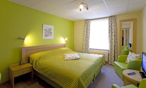 a green bedroom with a bed and a chair at Moulin de Daverdisse in Daverdisse