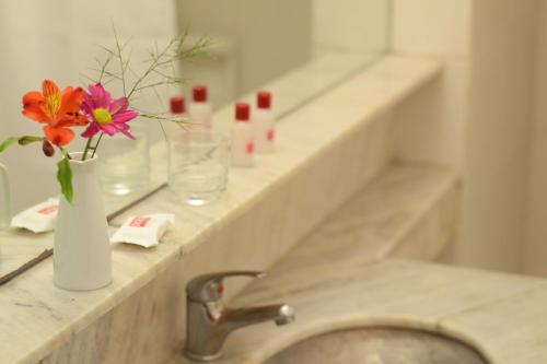 a bathroom counter with a sink with flowers in a vase at Hotel Dorá in Mar del Plata