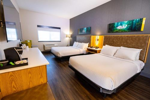 a hotel room with two beds and a desk at Creekside Hotel & Suites in Canyonville