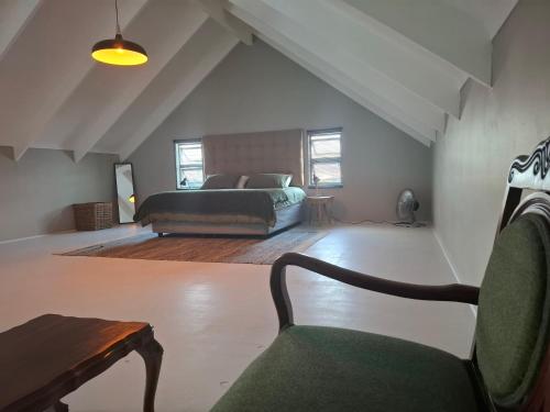 a bedroom with a bed and a chair in a room at 1 Deck Street in St. Helena Bay
