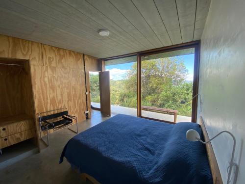 una camera con un letto blu e una grande finestra di Refúgio Contemporâneo na Serra da Bocaina a Silveiras