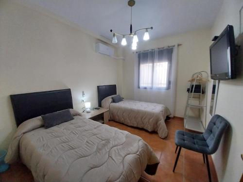 een slaapkamer met 2 bedden, een tv en een stoel bij Pensión Dani in Casinos