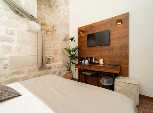 a bedroom with a bed and a desk with a television at Historic Han Hideaway in Vrana