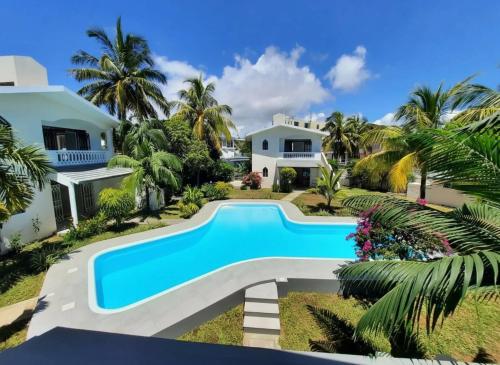 a villa with a swimming pool in front of a house at Mermaid Cove - GARDEN in Blue Bay