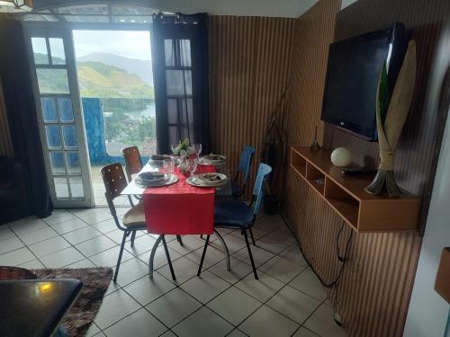 a dining room with a red table with chairs and a television at Beleza de Angra Apartamento Aconchegante in Angra dos Reis