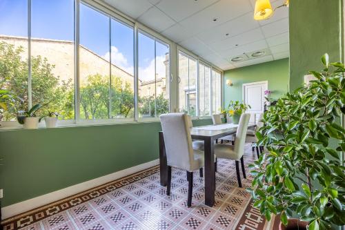 Un comedor con mesa y sillas y ventanas. en B&B La Halte Montaigne, en Burdeos