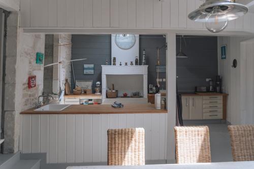 a kitchen with a counter and chairs in a room at L'Olivier de Milou in Le Bois-Plage-en-Ré