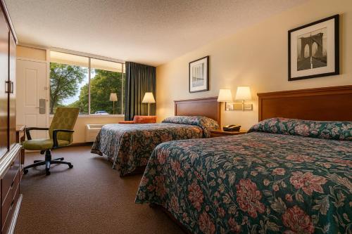a hotel room with two beds and a chair and a window at MHO Hotel Dover in Dover