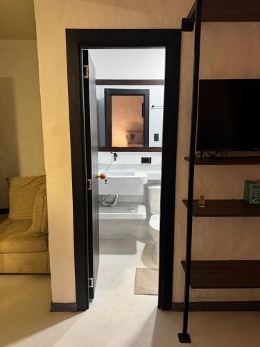 a bathroom with a toilet and a mirror and a television at La Aldea in Mocoa