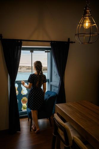 une femme assise sur une chaise devant une fenêtre dans l'établissement Apartamento Familiar con balcón y vista a la Ciudad, Centro, à Cusco