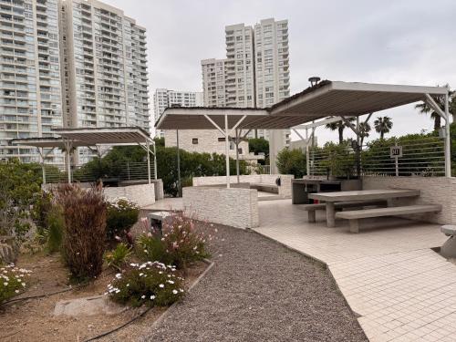 eine Terrasse mit Picknicktischen und Sonnenschirmen in einer Stadt in der Unterkunft Depto Peñuelas in Coquimbo