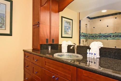 Un baño con lavabo y un espejo grande. en Kaanapali Royal D302 · KRL D302 Updated Kaanapali 2BD on Golf Co, en Lahaina