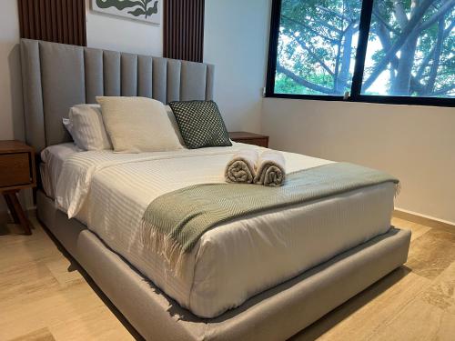 a bed in a bedroom with two towels on it at Departamento 2 hab con alberca y roof garden en Temozón in Mérida