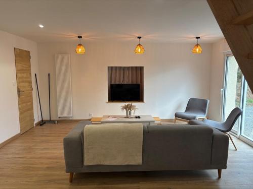 a bedroom with a bed and two chairs and a television at Gîte du Haut-Plantais in Saint-Aubin-de-Terregatte