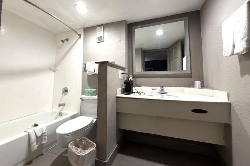 a bathroom with a sink and a toilet and a mirror at Townhouse Garden Inn & Suites San Antonio I 35 in San Antonio