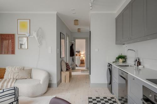 スンドビュベリにあるStylish 2BR Apartment in Central Sundbybergの白いリビングルーム(ソファ付)、キッチンが備わります。