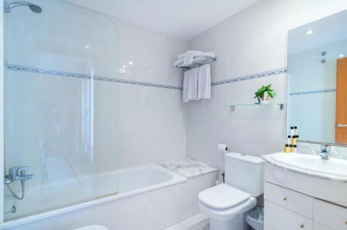 a bathroom with a tub and a toilet and a sink at Apartaments Ancora in Palamós