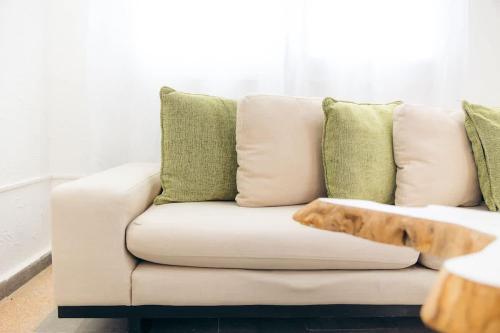 a white couch with green pillows and a dog laying on it at Cayenne Cozy Apt with Generator and Cistern in Bayamon in Sierra Linda