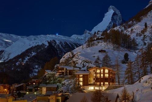 a town in the snow at night with a mountain at La Vue Luxury Living Apartments in Zermatt