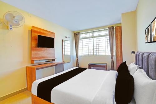 a bedroom with a white bed and a tv at Hotel O Indian Suites in Bengaluru