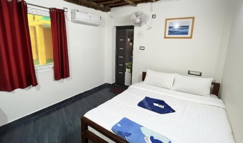 a bedroom with a white bed with a red curtain at SERENITY BAY HOME 2bhk in Pondicherry