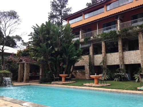 a hotel with a swimming pool in front of a building at Pousada Canto das Corujas in São Roque