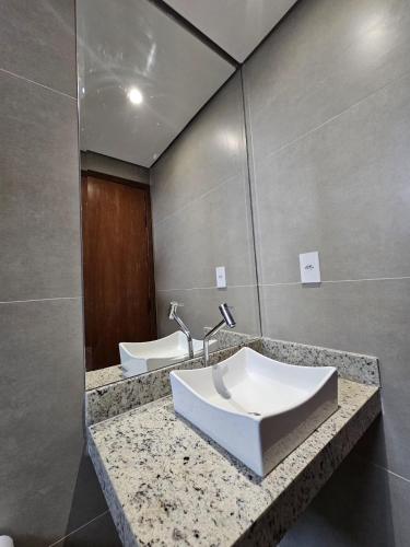 ein Badezimmer mit Waschbecken und Spiegel in der Unterkunft HOTEL POLASTRELLI in Governador Valadares