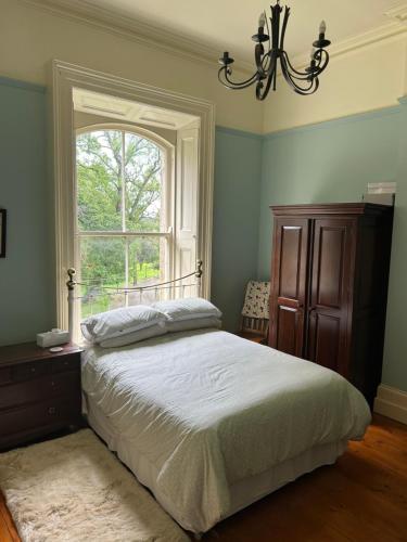 a bedroom with a bed and a window at Ballynacree House and Cottages in Balnamore