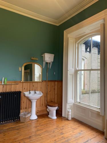 a bathroom with a sink and a toilet and a window at Ballynacree House and Cottages in Balnamore