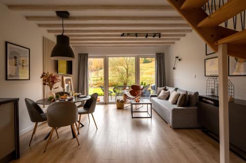 een woonkamer met een bank en een tafel bij Hill & Chill Kudowa Zdrój - nowoczesne stodoły ze strefą SPA, balia, sauna in Kudowa-Zdrój