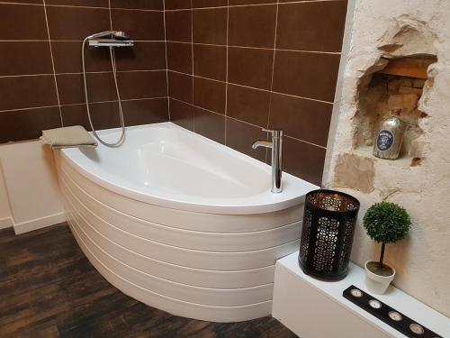 a white bath tub in a bathroom with brown tiles at Calmacé in Gignac