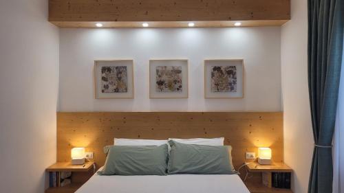 a bedroom with a bed with three pictures on the wall at B&B I FAGGI in Lavarone