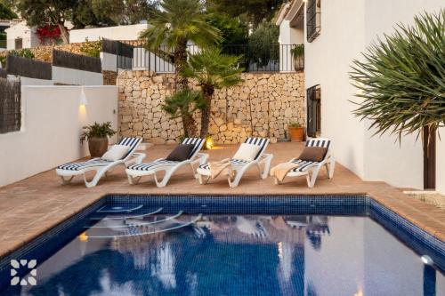 Una piscina con tumbonas junto a una casa. en Villa Las Salinas by Abahana Villas, en Rada de Moraira