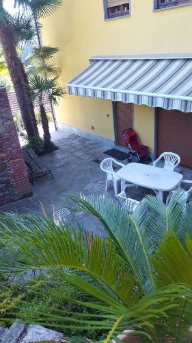 a patio with a table and chairs and palm trees at Casa dei Mulini in Mergozzo
