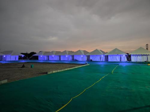 Eine Reihe von Zelten mit blauen Lichtern in der Wüste in der Unterkunft White Thar Camp in Dhordo