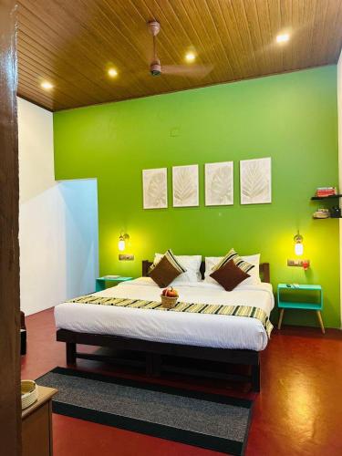 a bedroom with a bed with a green wall at 4elementis beach homestay in Mararikulam