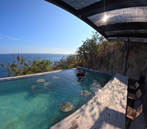 a man in a swimming pool next to the ocean at Casa A'more in Cuatunalco