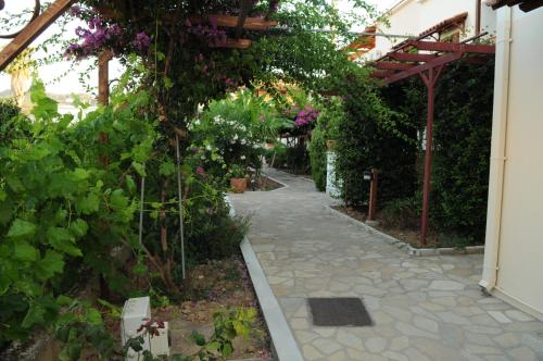 a garden with a pathway with flowers and a pergola at Hotel Athena in Kokkari