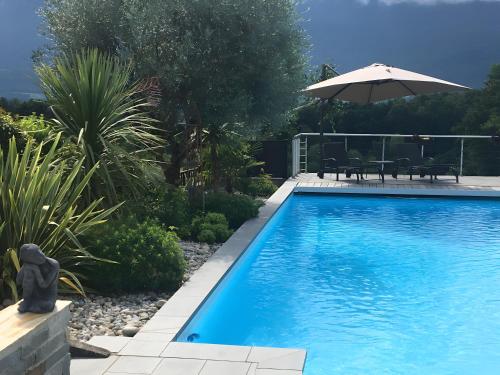 einen Pool im Garten mit Sonnenschirm in der Unterkunft Gîte Le Rêve, Entre Lac Et Montagne in Viviers-du-Lac