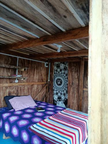 a bed in a room with a wooden ceiling at Eco Albergue Azul in Cuispes