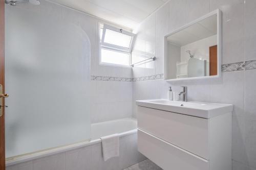 a white bathroom with a sink and a mirror at Piornais by Homie in Panasqueira